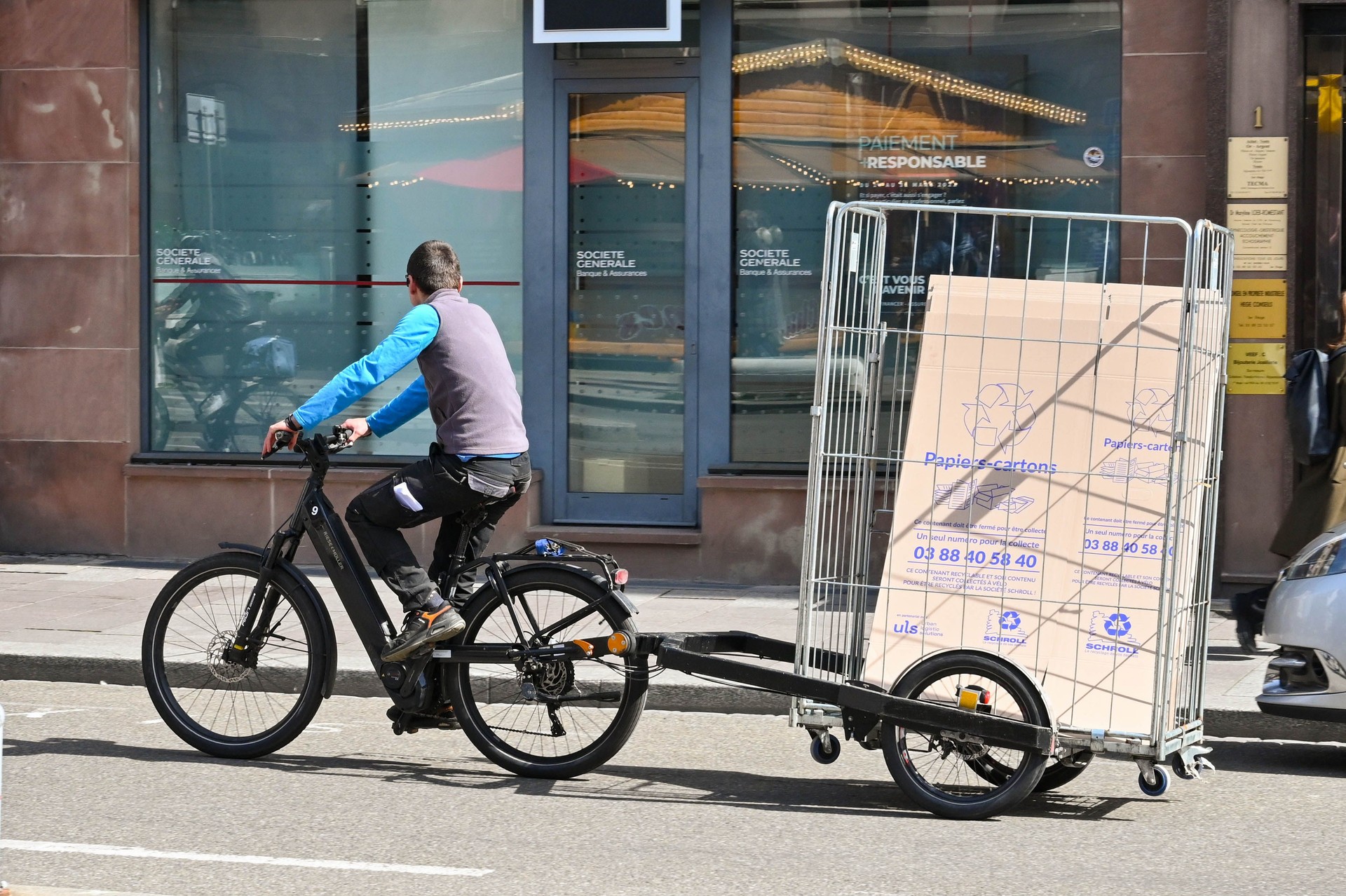 Person riding a bicycle with a trailer carrying goods for delivery